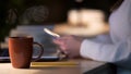 Cup of coffee standing on cafe desk, woman browsing internet on cellphone Royalty Free Stock Photo