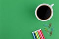 A cup of coffee and stationery tools over green background Royalty Free Stock Photo