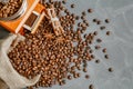 Cup of coffee with steam, coffee beans, chocolate pieces, cinnamon sticks, white and brown sugar, and scoop on burlap background. Royalty Free Stock Photo