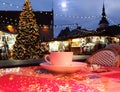 Cup of coffee on street cafe table top Christmas tree decor night  in Tallinn old town square blue sky blurred city light  holiday Royalty Free Stock Photo