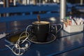 Cup of coffee on a summer terrace with a mobile phone and headphones