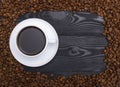 Cup of coffee surrounded coffee beans on black wooden table Royalty Free Stock Photo