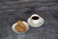 Cup of coffee on the table with biscuits cookies black bricks background