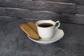 Cup of coffee on the table with biscuits cookies black bricks background