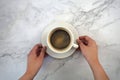 Cup of coffee on the table with hands placing it, with marble background Royalty Free Stock Photo