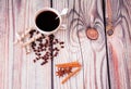 A cup of coffee is on the table next to a scatter of roasted coffee beans, wafer rolls, cinnamon sticks and anise stars Royalty Free Stock Photo