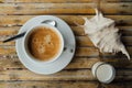 A cup of coffee on the table next to a seashell and a glass of milk on a bamboo table.