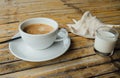 A cup of coffee on the table next to a seashell and a glass of milk on a bamboo table.