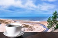 Cup of coffee on the table with view of sandy beach with dunes and pine tree on Baltic sea coast Royalty Free Stock Photo