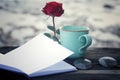 A cup of coffee or tea and red rose with blank paper book on bright background. Notebook, red rose flower, glasses and coffee cup. Royalty Free Stock Photo