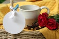 Cup of coffee or tea and red rose flowers in a rattan basket on yellow background. With white blank tag label paper for your text. Royalty Free Stock Photo