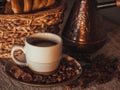Cup of coffee on textile with beans, dark candy sugar, pots, basket and cake Royalty Free Stock Photo