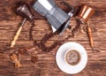 Cup of coffee, three coffeepots, cinnamon, anise, coffee beans on a wooden tray.