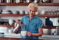 A cup of coffee to start the day. an attractive senior woman pouring herself a cup of coffee while standing in the Royalty Free Stock Photo