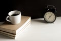 A cup of coffee on top the books with retro alarm clock. Royalty Free Stock Photo