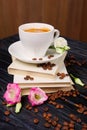 Cup of coffee on top of pile of books with coffee beans and flowers scattered on the table Royalty Free Stock Photo