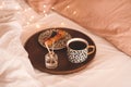 Cup of coffee in tray with home fragrance in glass bottle with sticks and tasty cake in bed close up. Royalty Free Stock Photo