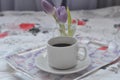 a cup of coffee tray with spring flowers on pink bedding. Relaxing, or working, or writing diary or blog in bed at home