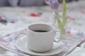 a cup of coffee tray with spring flowers on pink bedding. Relaxing, or working, or writing diary or blog in bed at home