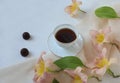 A cup of coffee with two chocolates, daylily flowers on a delicate scarf on a white background, a place for text, a top view-the