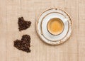 Cup of coffee and two coffee hearts on burlap background. Top view, copy space