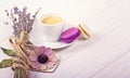 Cup of coffee with two macarons, bunch of lavender and wooden heart. Violet and purple concept on white background