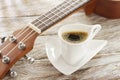 Cup of coffee and ukulele on rustic wood. Royalty Free Stock Photo