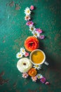 Cup of coffee with variation of flowers on green background with copy space