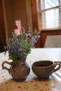 A cup of coffee and a vase of flowers on a table Royalty Free Stock Photo