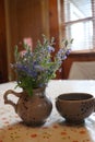 A cup of coffee and a vase of flowers on a table Royalty Free Stock Photo