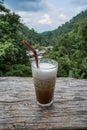 A cup of coffee with a view of green landscape in the background. Iced coffee in cafe at Mae Kampong village, Chiang Mai, Thailand Royalty Free Stock Photo