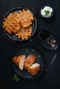 Cup of coffee, waffle and croissant on wooden black table