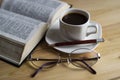 A Cup of coffee on a warm background. The open Bible. Glasses. Royalty Free Stock Photo