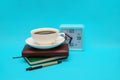 A cup of coffee, a watch, and a notebook on a blue background. The concept of the business theme