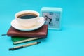 A cup of coffee, a watch, and a notebook on a blue background