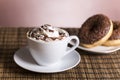 Cup of coffee with whipped cream and chocolate donut with nuts Royalty Free Stock Photo