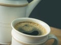 A cup of coffee, in a white cup on wooden table, blurred background, close up