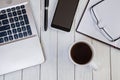 Cup of coffee on white desktop with laptop, notebook, smartphone, pen and glasses. Business concept Royalty Free Stock Photo