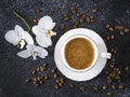 A cup of coffee, white orchid flowers, coffee beans. Romantic composition on a black background Royalty Free Stock Photo