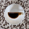 A Cup of coffee on a white plate and coffee beans around it Royalty Free Stock Photo