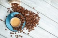 Cup of coffee on white wooden background with scattered coffee beans. copy space text