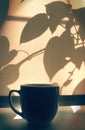 Cup of coffee on windowsill closed curtains sunrise or sunset shadows and light , crossing of plant shadows on  beige textile Royalty Free Stock Photo