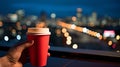 cup of coffee in woman hand street cafe at night ,view on rainy city blurred light and houses