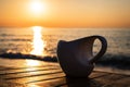 Cup of coffee on wood table at sunset or sunrise beach