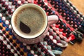 Cup of coffee on wooden background with textile hand-woven rag rug. Copy space, top view Royalty Free Stock Photo