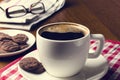 Cup of coffee on a wooden table with biscuits, glasses and newspaper Royalty Free Stock Photo