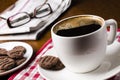 Cup of coffee on a wooden table with biscuits, glasses and newspaper Royalty Free Stock Photo