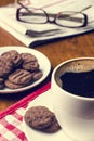 Cup of coffee on a wooden table with biscuits, glasses and newspaper Royalty Free Stock Photo