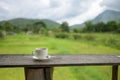 Cup of coffee on a wooden table over mountains landscape and rice field with sunlight. Beauty nature background Royalty Free Stock Photo