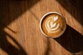 Cup of coffee on wooden table in sunlight. Fresh cappuccino with latte art on brown background. Beautiful foam. Coffee Royalty Free Stock Photo